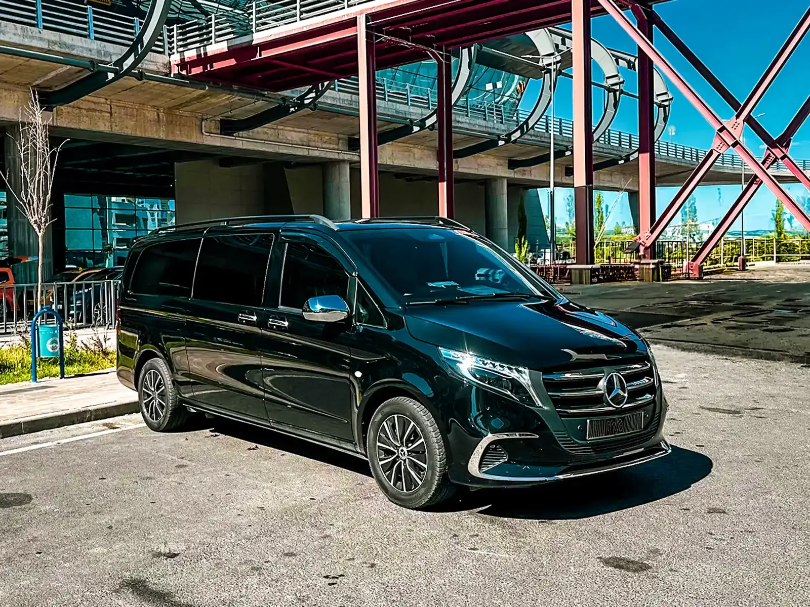 Black Mercedes Vito private transfer vehicle parked at airport departures, front three-quarter view