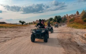 Guided Cappadocia ATV tour group riding through the valleys near Göreme, with fairy chimneys visible in the background