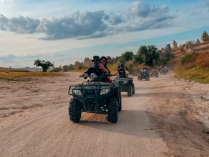 Guided Cappadocia ATV tour group riding through the valleys near Göreme, with fairy chimneys visible in the background