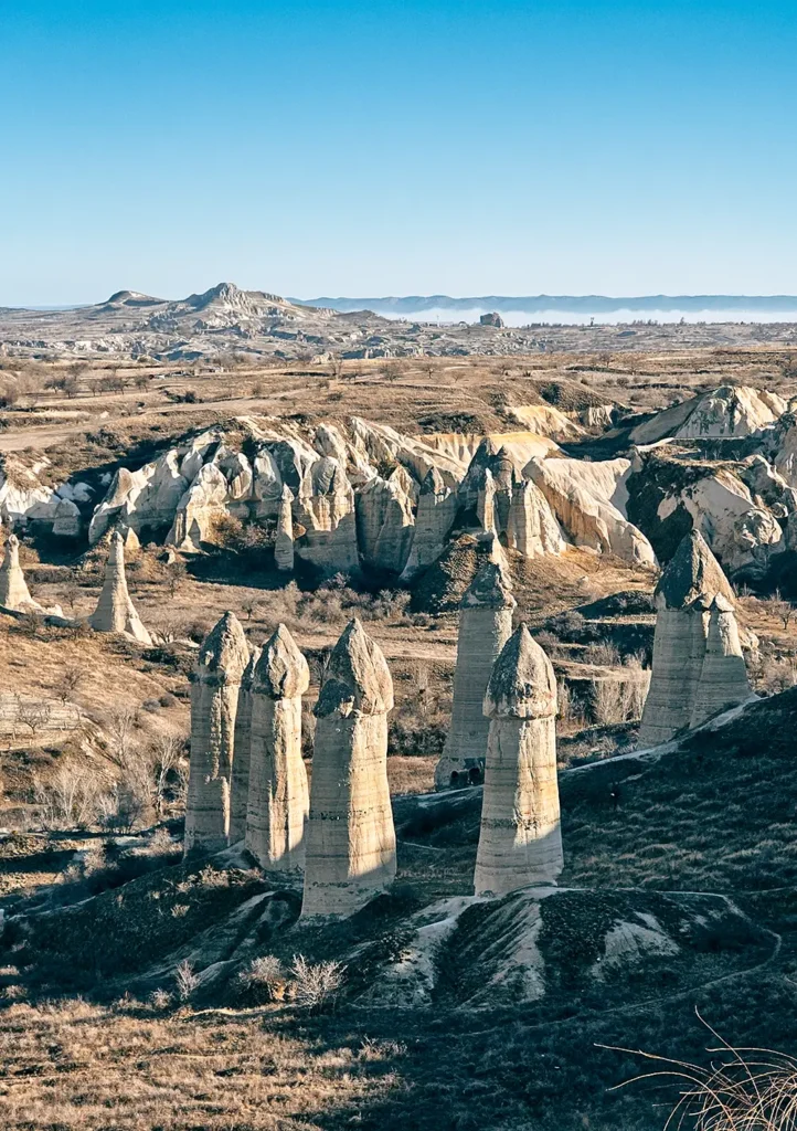 Iconic tall fairy chimneys of Love Valley in Cappadocia under a blue sky.