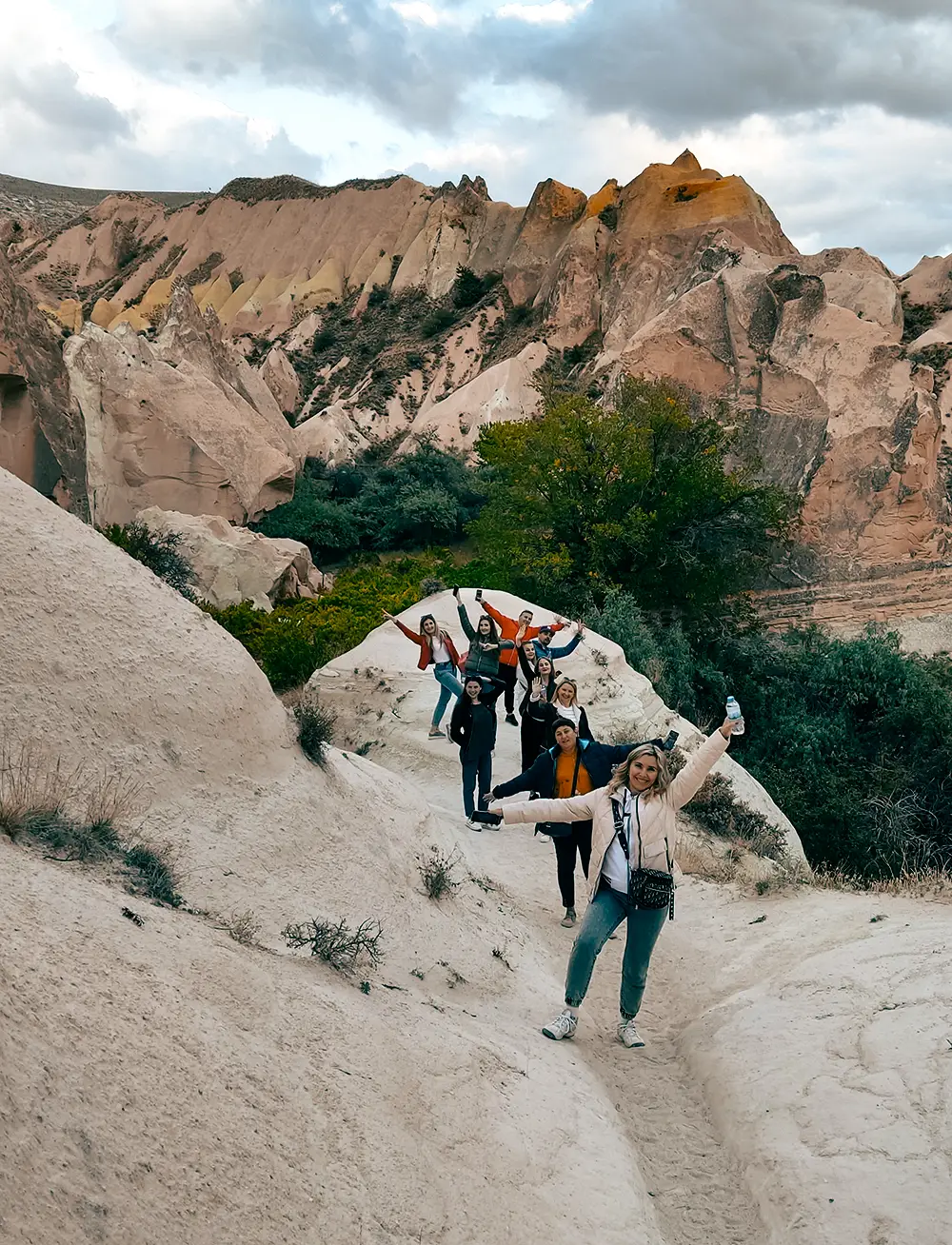 Travelers posing on the pink-hued rock formations of Rose Valley, Cappadocia.