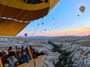 Balloon passengers in the basket with Uçhisar Castle behind, Cappadocia