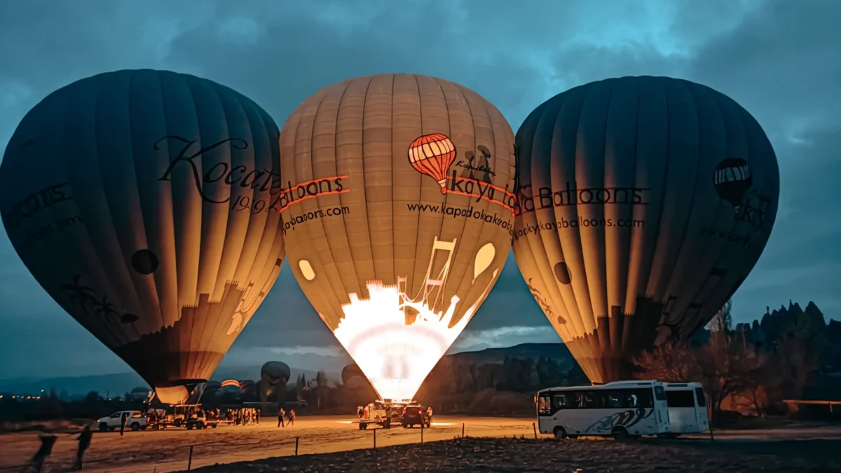 Three SHGM-licensed Cappadocia balloons inflating at pre-dawn — Kocatepe, Kaya, and Kapadokya Balloons preparing for sunrise flight