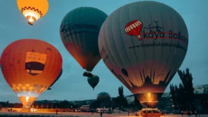 SHGM-licensed Cappadocia hot air balloons at sunrise launch — Kapadokya Kaya Balloons and World Heritage Academy preparing for flight over Göreme UNESCO site