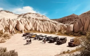 Cappadocia jeep safari fleet parked in Rose Valley — Land Rover Defenders on unpaved valley floor with tuff cone formations in the background