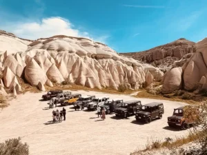 Cappadocia jeep safari fleet parked in Rose Valley — Land Rover Defenders on unpaved valley floor with tuff cone formations in the background